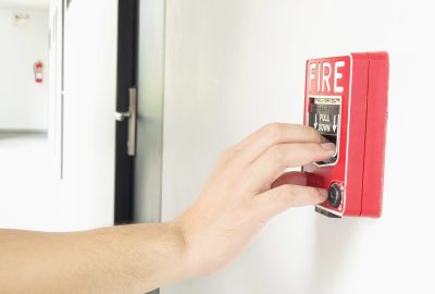 Man is reaching his hand to push fire alarm hand station